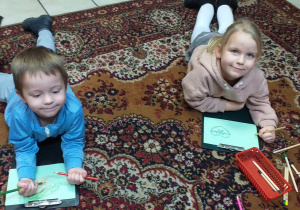 Dzieci rysują kredkami laurki dla babci i dziadka.
