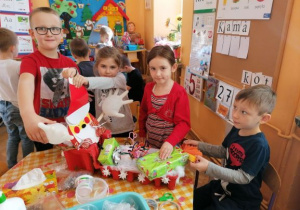 dzieci dekorują pojazd św. Mikołaja zrobionego z pudełka