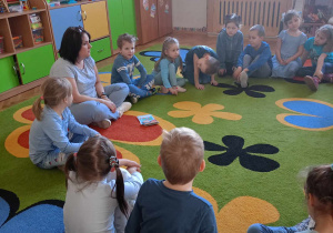 Pani Gosia z dziećmi w kole na dywanie.
