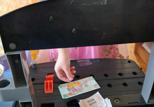 Dziewczynka kupuje swój bilet w zabawkowym kinie.