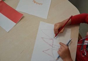 Dzieci wykonują pracę plastyczna na temat "Co kojarzy mi się z Polską?"