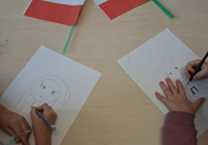 Dzieci wykonują pracę plastyczna na temat "Co kojarzy mi się z Polską?"