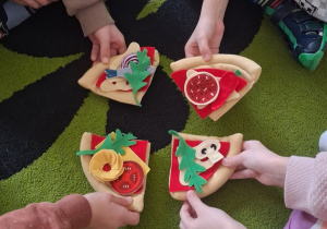 Dzieci składają zabawkową pizzę.
