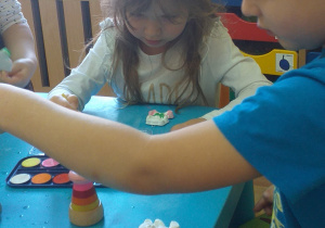Dzieci malują gipsowe figurki misiów.
