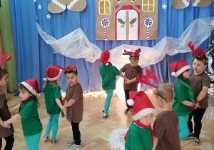 Dzieci przebrane za renifery i elfy tańczą w parach.