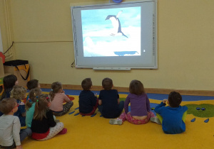 Dzieci oglądają prezentację multimedialną nt. życia pingwinów.