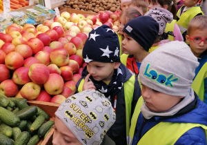 Dzieci oglądają na straganie jabłka.
