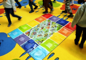 dzieci układają kolorowy dywanik na mapie miasteczka