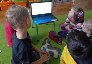Dzieci oglądają film edukacyjny dotyczący andrzejkowych wróżb.